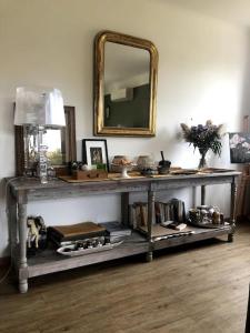 een tafel met een spiegel en een plank met boeken bij Maison au coeur de la Provence in Jonquerettes