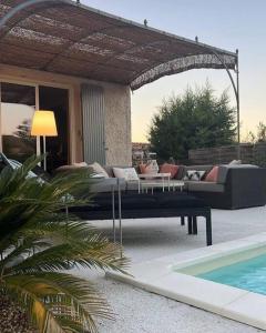um pátio com um sofá e uma mesa ao lado de uma piscina em Maison au coeur de la Provence em Jonquerettes