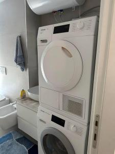 una lavatrice e asciugatrice in un piccolo bagno di Eden Apartment: 2BR, Family friendly a Tirana
