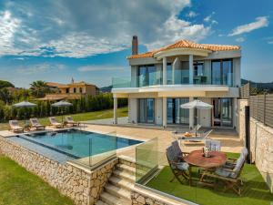 a villa with a pool and a table and chairs at Violet Beach Front Private Villa in Laganas