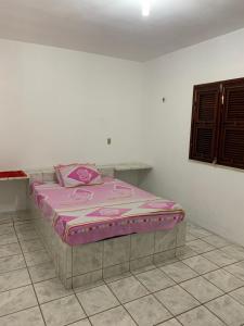 a bed in a room with a pink blanket on it at Casa em Paracuru in Paracuru