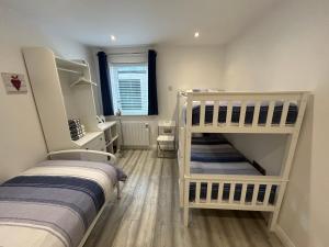 two white bunk beds in a room with a bathroom at Ballycastle, Beachside Apartment in Ballycastle