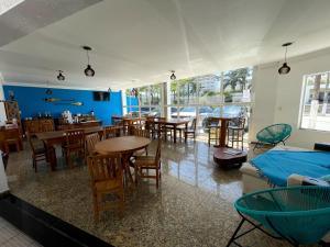 a room with tables and chairs and a dining room at Bene Beach - Pousada Guarujá in Guarujá