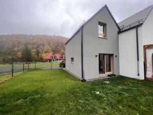 una casa blanca con un patio verde en Villa Monte Apartament z ogrodem en Kudowa-Zdrój
