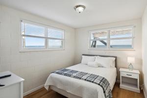 1 dormitorio blanco con 1 cama y 2 ventanas en 3 Little Pirates, en Folly Beach