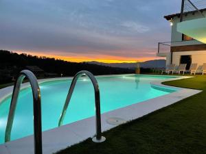 a swimming pool in front of a house with a sunset at Villa Mas Paz in Terra Brava