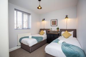 a bedroom with two beds and a desk at Whitey Bay Coastal Bliss in Whitley Bay