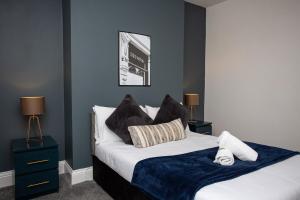 a bedroom with a bed with a blue accent wall at The Ferndale - Spacious 3 Bed Apartment in Pallion