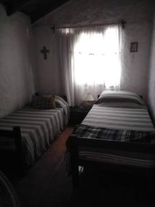 2 camas en una habitación con ventana y cruz en Casa de playa en Punta Rubia Calle Garzón y Rocha, en Rocha