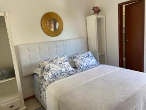 a bedroom with a bed with two pillows and a mirror at Residencial Jurerê Belo in Florianópolis