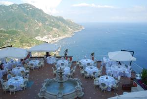 un restaurante con mesas y sillas blancas y el océano en Hotel Villa Fraulo, en Ravello