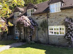 een oud stenen huis met bloemen in de tuin bij Quarry House in Presteigne