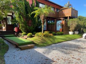 a house with a yard with grass and plants at Residencial Jurerê Belo in Florianópolis