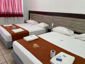 a hotel room with three beds with certificates on them at Hotel Albatros in Pe&ntilde;ita de Jaltemba