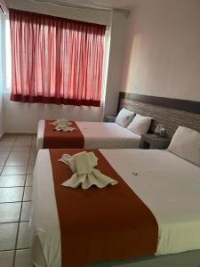 two beds in a hotel room with towels on them at Hotel Albatros in Pe&ntilde;ita de Jaltemba