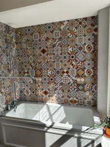 a bathroom with a tub and a tile wall at Castle Hotel in Aberaeron