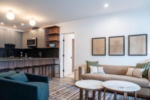 a living room with a couch and tables and a kitchen at Escape to Revy - Beautifully Designed Condo in Revelstoke