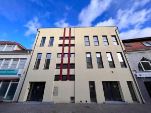 un grand bâtiment blanc avec des bandes rouges sur lui dans l'établissement One Step Apartman - City Center with Self Check-In, à Szombathely