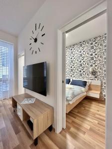 1 dormitorio con 1 cama y reloj en la pared en One Step Apartman - City Center with Self Check-In en Szombathely