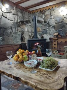 einen Tisch mit Obst- und Weingläsern und einen Kamin in der Unterkunft Guest House Shuan in Chokhuldi