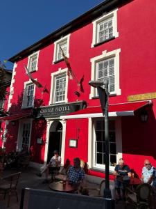 a group of people sitting outside of a red building at Castle Hotel in Aberaeron