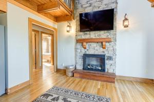 a living room with a stone fireplace and a flat screen tv at Bryson City Cabin Deck and Mountain-View Hot Tub in Nantahala