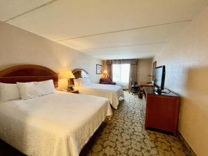 a hotel room with two beds and a flat screen tv at ACP Hotel Westchase in Houston