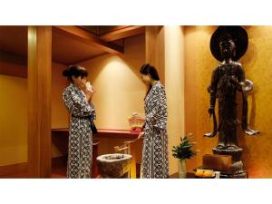 Dos mujeres inimonos parados en una habitación con una estatua en Mansuirou - Vacation STAY 32143v, en Misasa