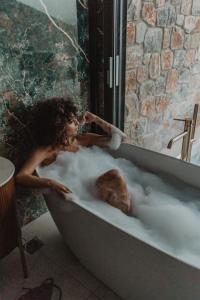 a woman laying in a bath tub filled with foam at Happy Cretan Suites in Agia Pelagia