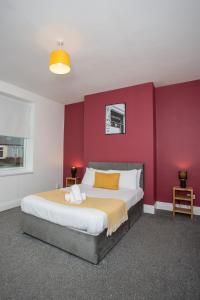 um quarto com uma cama grande e uma parede vermelha em The Ferndale Gf em Pallion