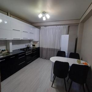 cocina con mesa, sillas y nevera en Apartament, en Chişinău