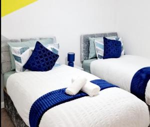 two beds with blue and white pillows in a room at Beautiful 2-Bed House in Gillingham in Gillingham