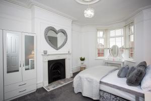 een witte slaapkamer met een hartspiegel aan de muur bij The Brighton in Gateshead
