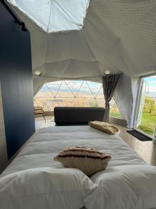 a bedroom with a large white bed with a large window at NaturHotel in Cuenca