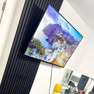 a flat screen tv hanging on a wall at Private Modern Ensuite Room near Etihad Stadium in Manchester