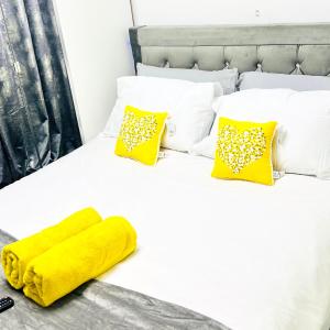 uma cama branca com um cobertor amarelo e almofadas em Private Modern Ensuite Room near Etihad Stadium em Manchester