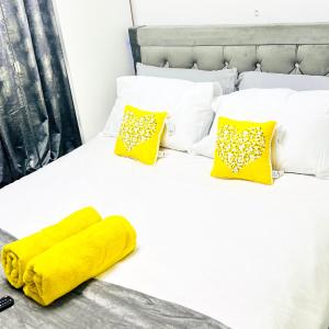 a white bed with a yellow blanket and pillows at Private Modern Ensuite Room near Etihad Stadium in Manchester
