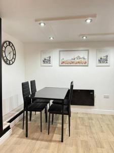 a black table and chairs in a room with a clock at Your Home-Big offers for Groups! in Leeds