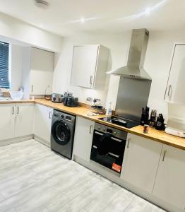 cocina con armarios blancos, lavadora y secadora en Private Modern Ensuite Room near Etihad Stadium en Mánchester