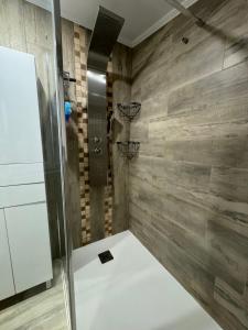 a shower in a bathroom with wooden walls at Charmante maison avec terrasse in Auterive