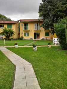 a yellow house with a grass yard and a sidewalk at Pousada Meu Cantinho in Conservatória