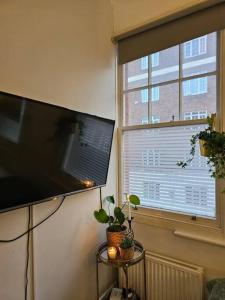 Beautiful and spacious flat في لندن: تلفزيون بشاشة مسطحة على جدار بجوار نافذة