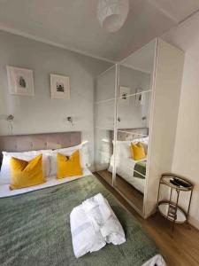 a bedroom with two beds with yellow pillows and a mirror at Beautiful and spacious flat in London