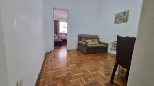 uma sala de estar com uma cadeira e pisos em madeira em Apartamento Nossa Senhora no Rio de Janeiro
