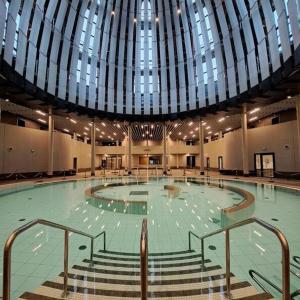 a swimming pool in a building with a large ceiling at Grande chambre privée 18 m2 dans maison proche Gare et Nancy Thermal in Tomblaine