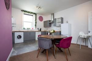 a kitchen with a table and purple chairs at The Elswick in Elswick
