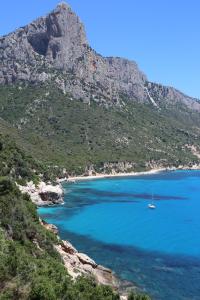 ein Boot in einem Wasserkörper mit einem Berg in der Unterkunft Casa Nonna Delfina in Tortolì