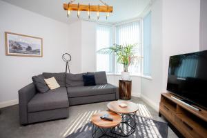 a living room with a couch and a tv at Stylish Cosy Two Bed Apartment - Coast Location in Whitley Bay