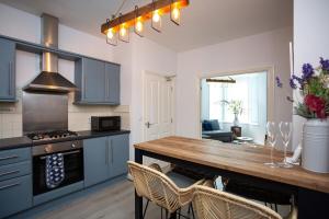 a kitchen with blue cabinets and a wooden table at Stylish Cosy Two Bed Apartment - Coast Location in Whitley Bay