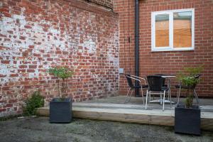 a patio with a table and chairs next to a brick wall at Stylish Cosy Two Bed Apartment - Coast Location in Whitley Bay